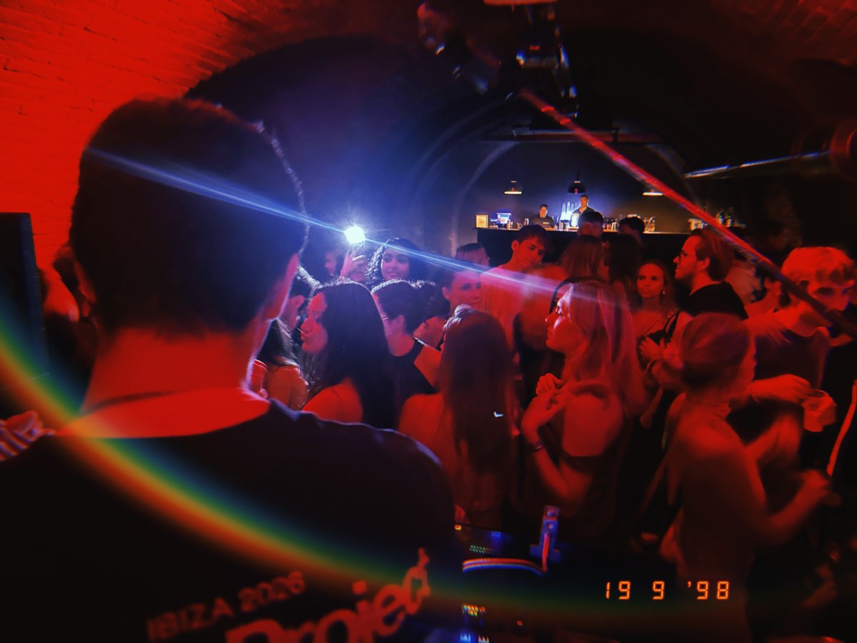 faces in the crowd lit by a single phone light at the bar