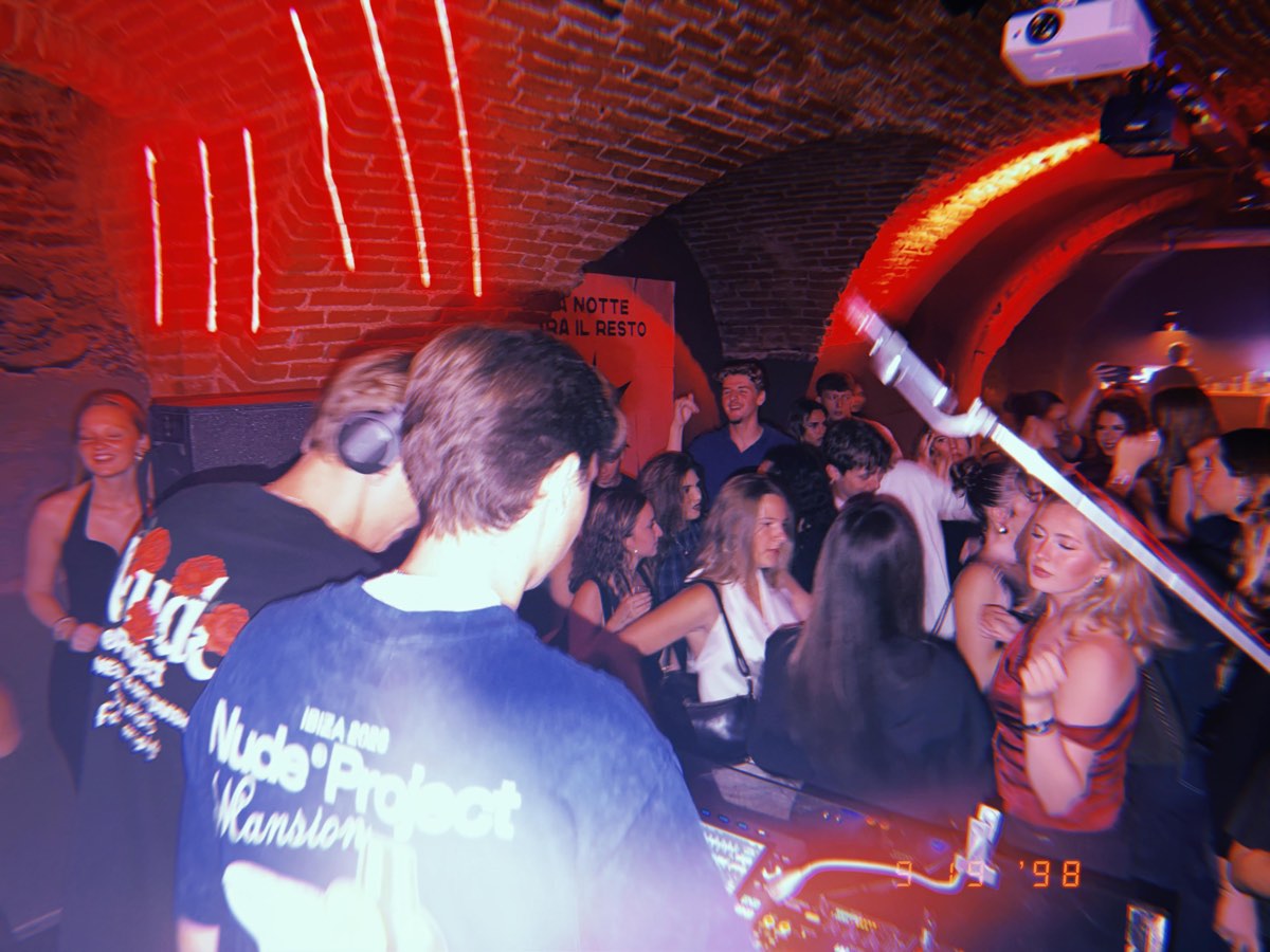 crowd dancing under a red-lit brick vault